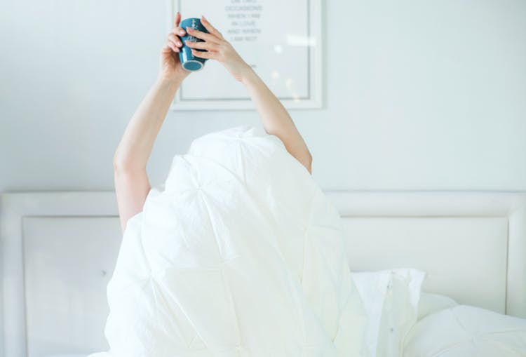 Person Holding Mug In Bed