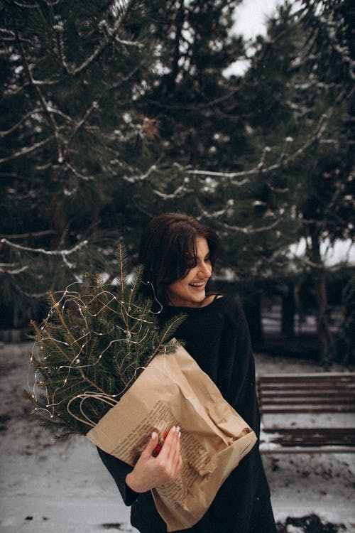 Woman Holding a Paper Bag with Spruce Twigs