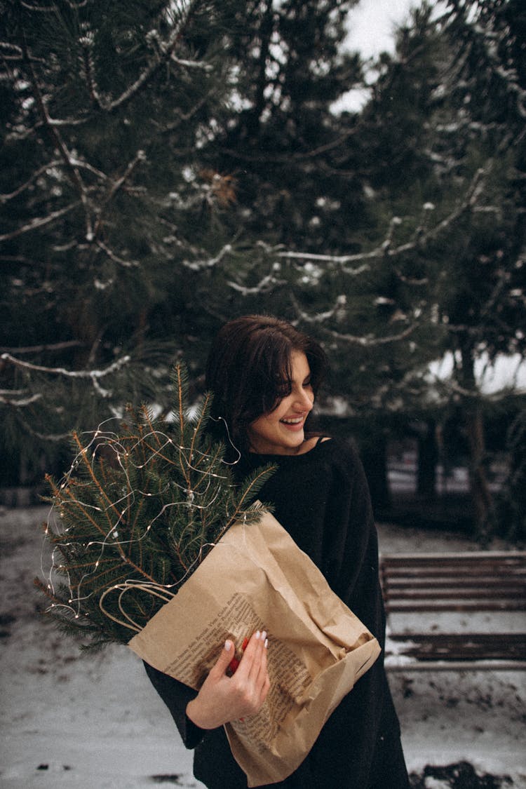 Woman Holding A Paper Bag With Spruce Twigs