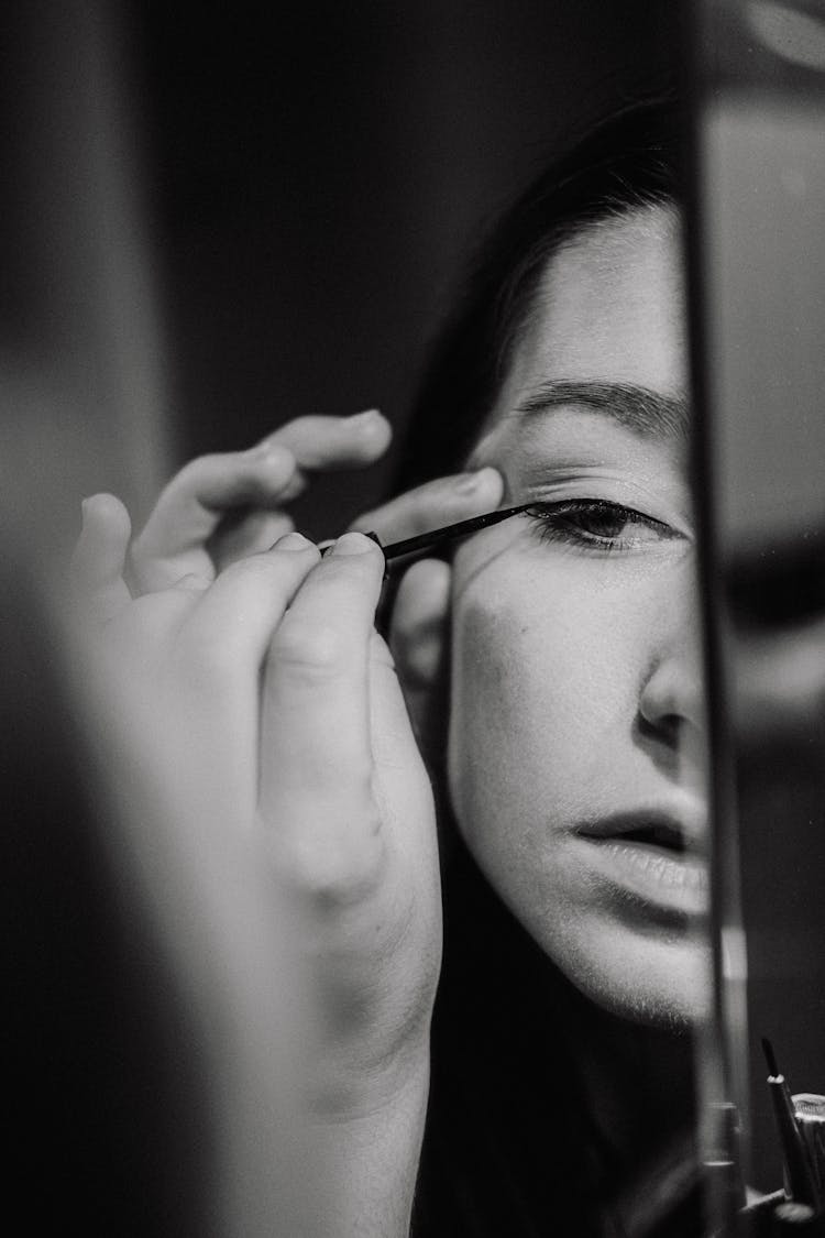 Grayscale Photo Of Woman Putting On Eyeliner