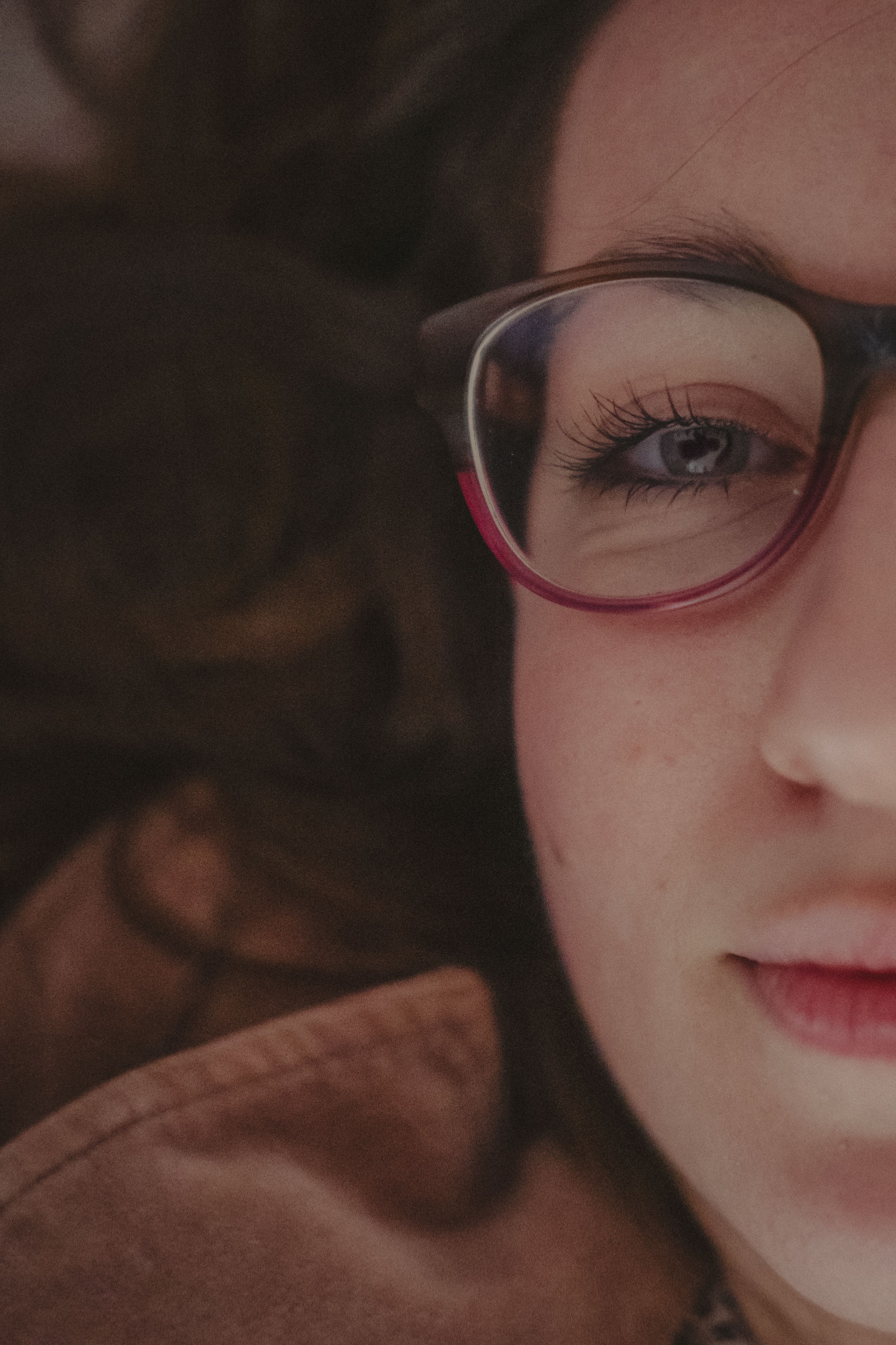 Artistic close-up of a woman wearing glasses, showcasing half her face in detail.