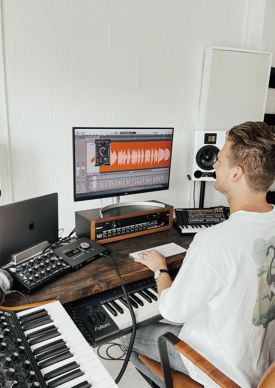 Muziekproducent die een digitale audio workstation gebruikt in een moderne thuisstudio.