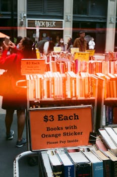 Street vendor selling books at an outdoor market in Boston, with $3 each sale sign.