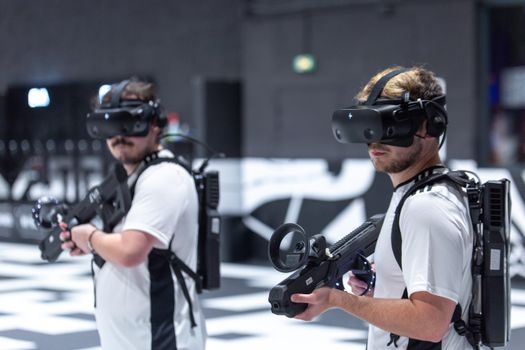 Two men playing a virtual reality game indoors in Paris, using VR headsets and gear.