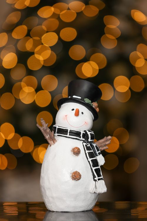 Free Delightful snowman figurine with bokeh lights, perfect winter decoration. Stock Photo