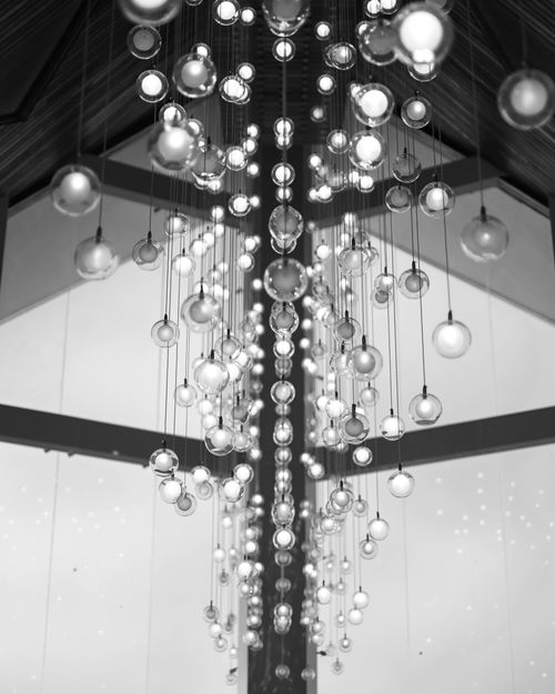 Free A sophisticated black and white photo of modern chandelier lighting in an indoor setting. Stock Photo