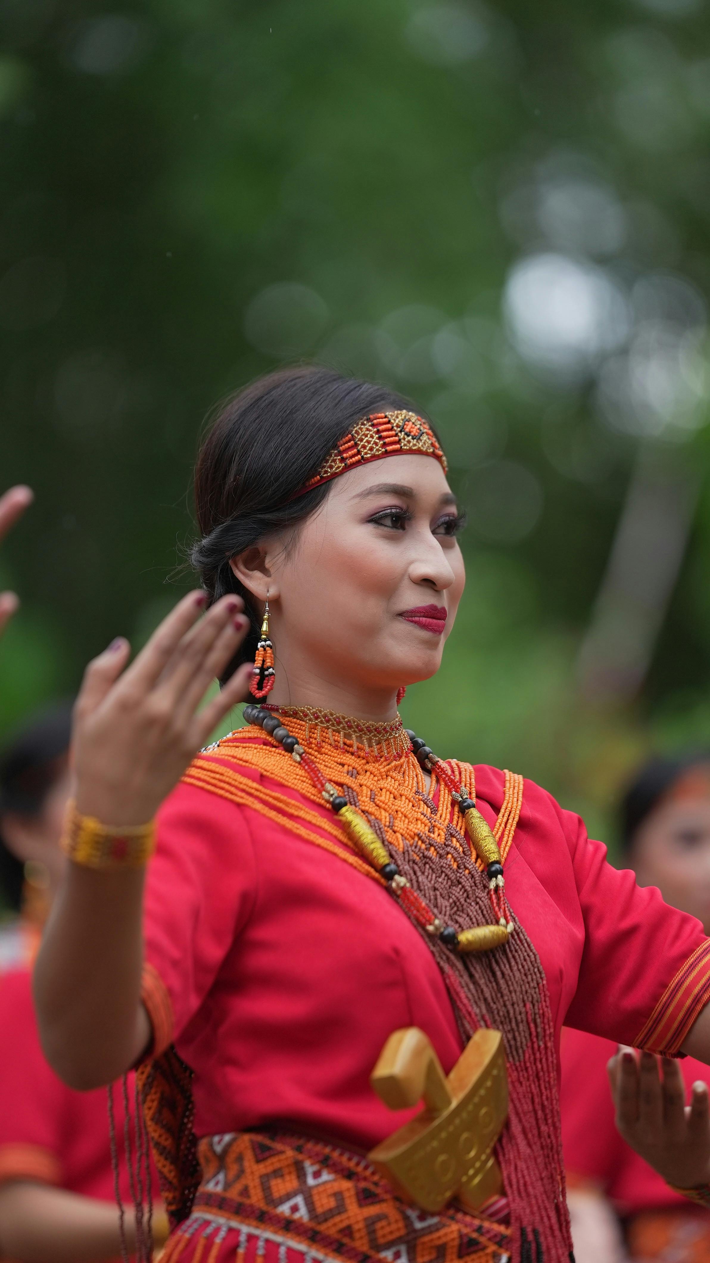 Asian woman in vibrant traditional clothing performing a cultural dance outdoors.