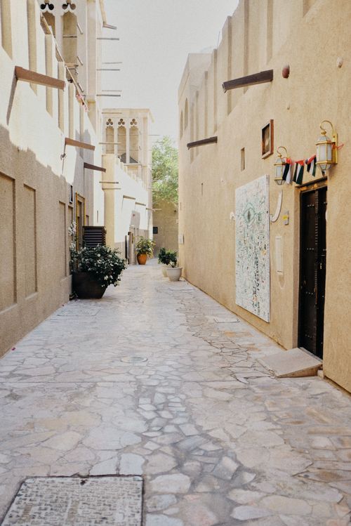 Free Discover a charming narrow alleyway with rustic stone pavements in a historic district, bathed in natural light. Stock Photo