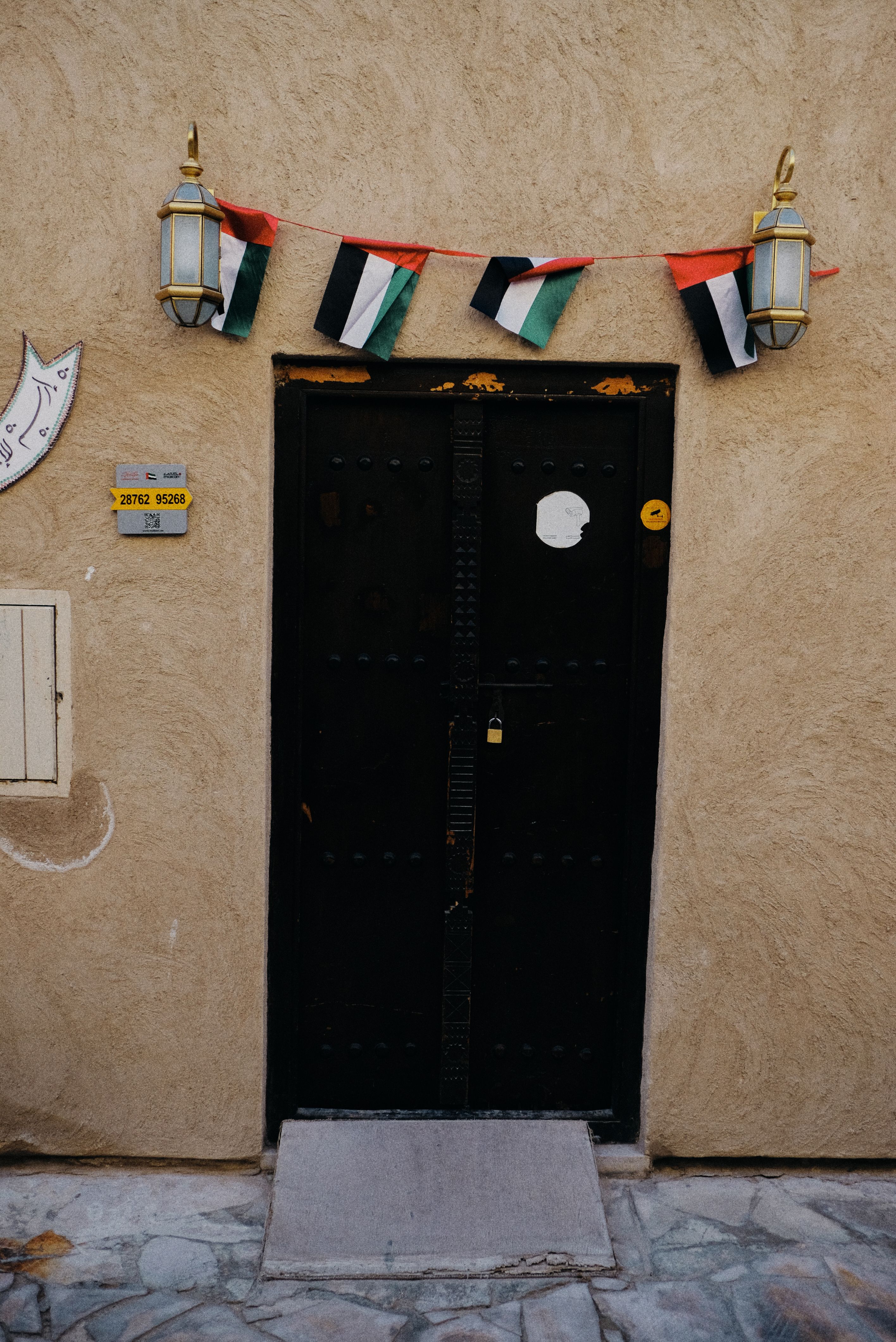 A historic black door decorated with UAE flags in Dubai, showcasing Arabian architectural elements.