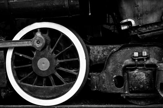 Detailed black and white close-up of a vintage steam train wheel showing intricate mechanical parts.