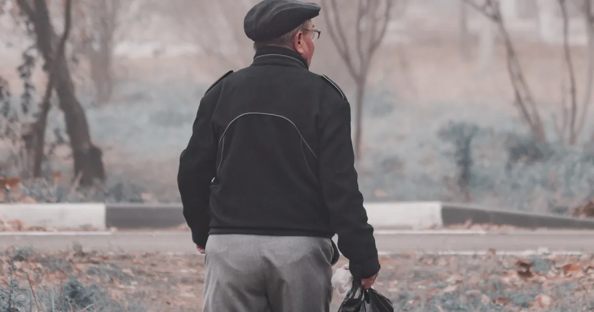 A man walking alone along a path on a foggy morning