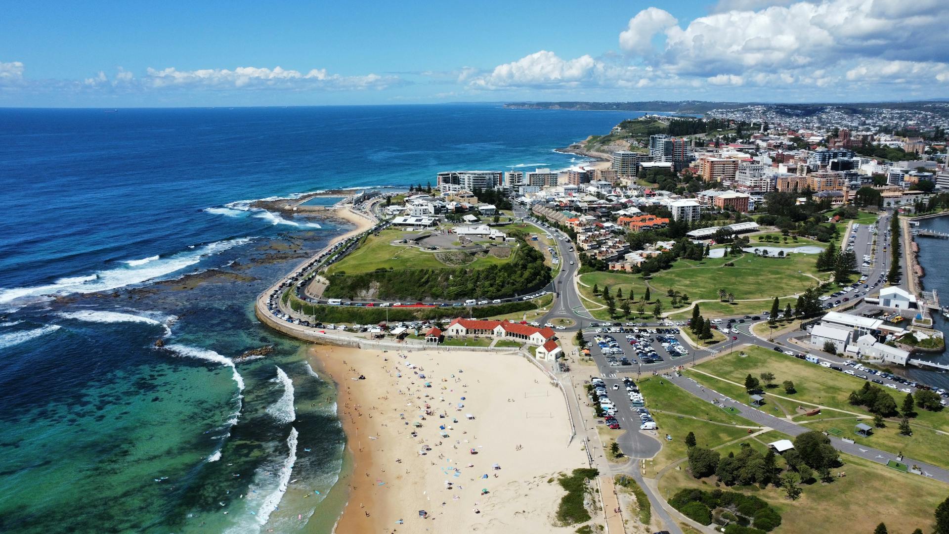 Stunning aerial shot of Newcastle beach, coast, and cityscape on a sunny day.