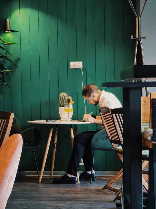 Free Adult man in a cafe writing notes at a table, providing a cozy and focused setting. Stock Photo