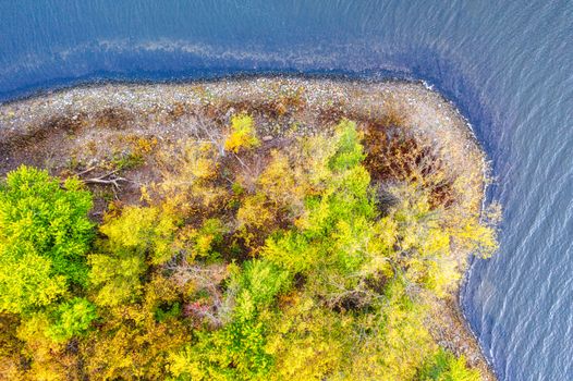 A vivid aerial shot of autumn foliage on a small island by a tranquil lake in Maple Springs, MN.