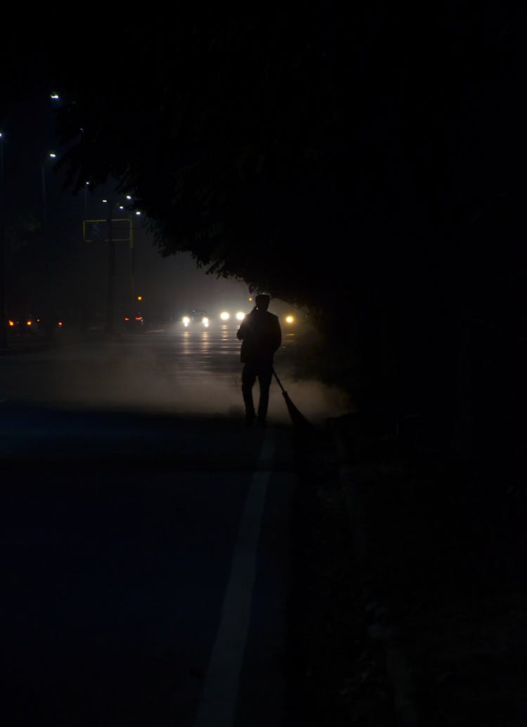 Man Sweeping The Road During Night Time