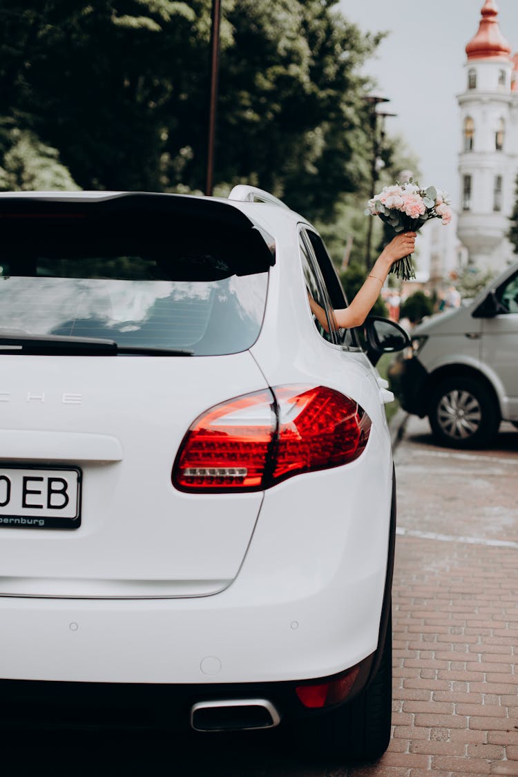 Woman Hand Holding Flower Bouquet Out Of Car Window