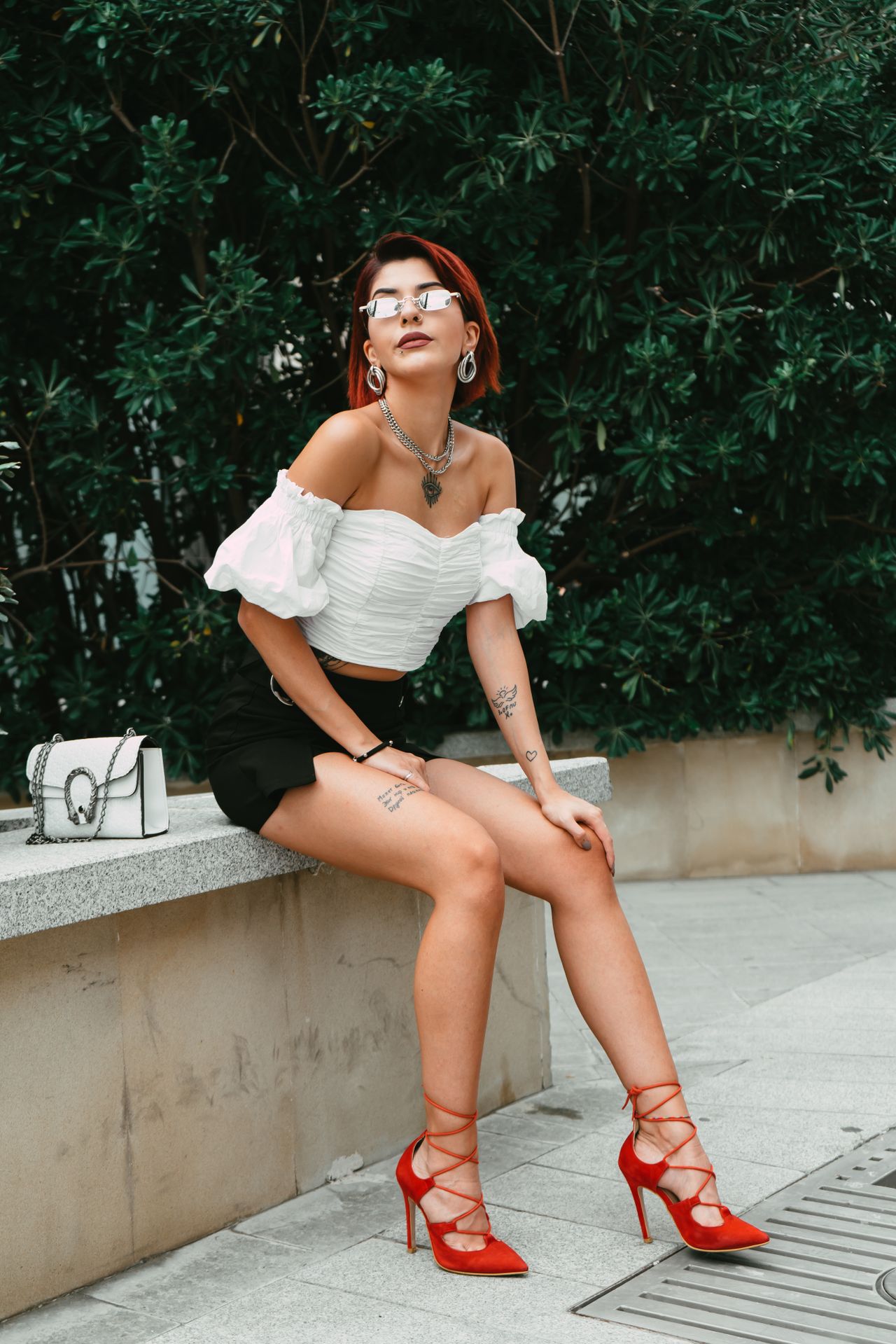 Woman in a white top, black mini skirt and red lace-up heels
