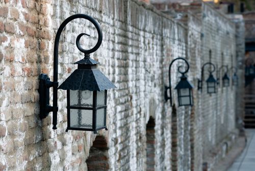 Free Close-up of vintage metal lanterns hanging on an old stone wall, creating a rustic atmosphere. Stock Photo