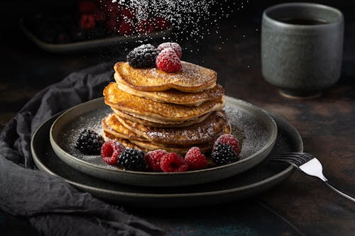 Castor Sugar Sprinkled on Pile of Pancakes with Fruits 