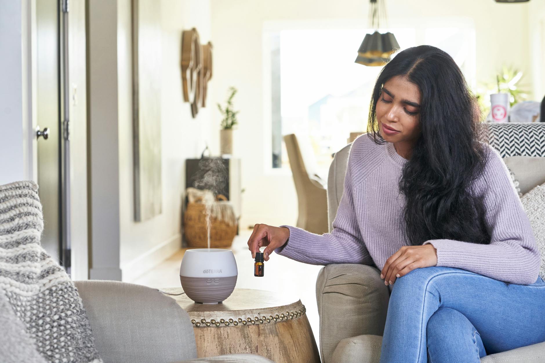 A Woman in Knitted Sweater Sitting on the Couch while Holding a Small Bottle