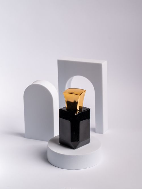 Free Minimalistic perfume bottle in black and gold set on a white geometric background. Stock Photo
