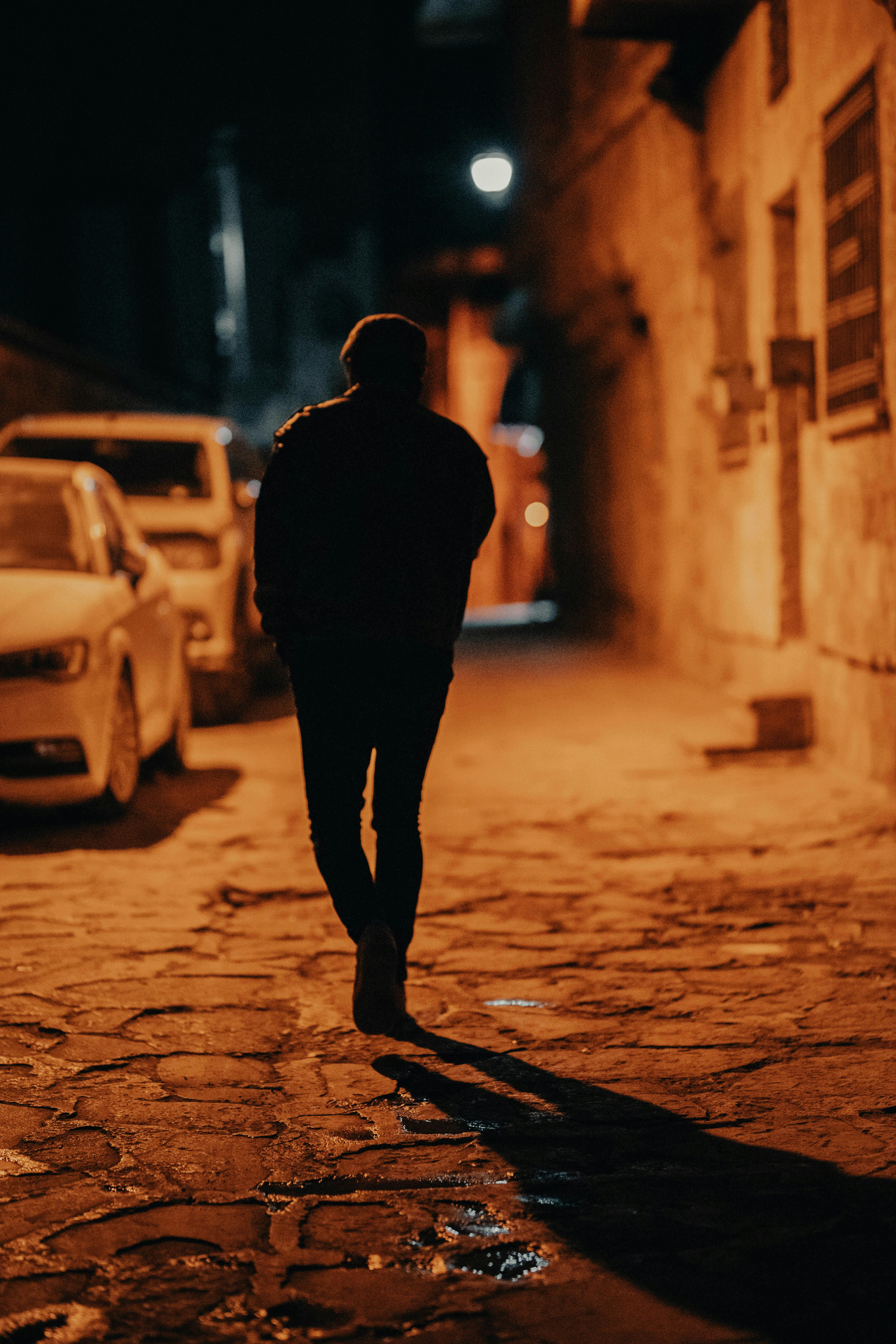 a man walking on the street during night time