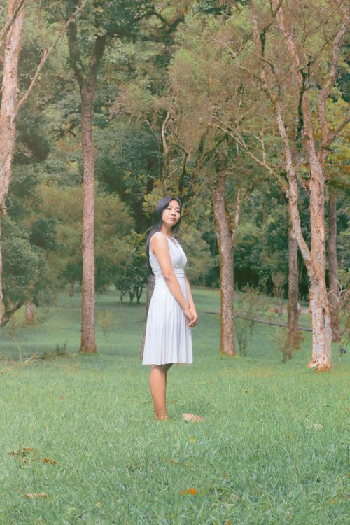 Free A woman in a white dress stands amidst lush greenery in Bali, Indonesia. Stock Photo