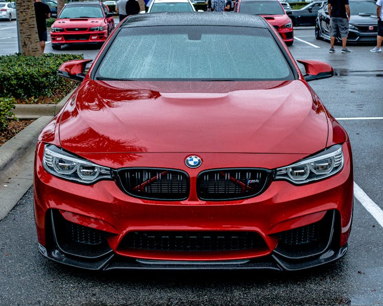 A Red Bmw Car Parked On A Parking Lot