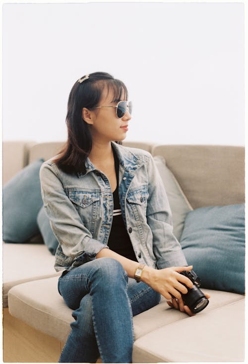 A Woman in Denim Jacket and Denim Jeans Sitting on the Couch