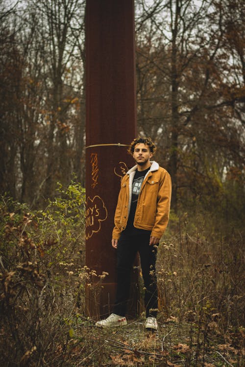 Man in Brown Jacket Standing Near Brown Pole