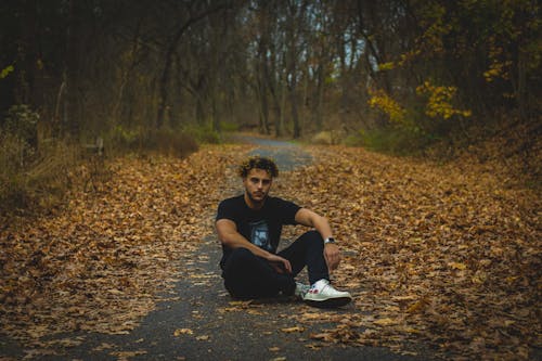 Man in Black Shirt and Pants Sitting on the Road