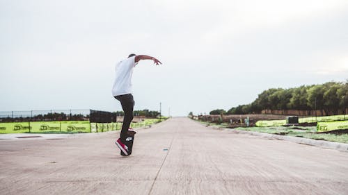 A Man in White Shirt and Black Pants Playing Skateboard