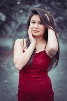 Portrait of a young woman in a red dress posing outdoors with a serene expression.