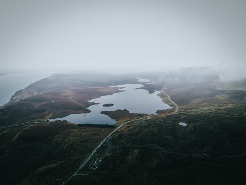 Aerial Shot of Lake Between Mountains on Foggy Day