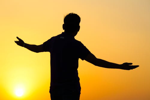 Silhouette of Man with Open Arms During Sunset