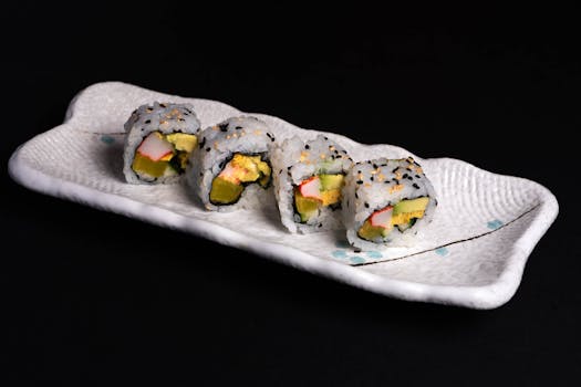 Tempting sushi rolls with avocado and crab sticks on a stylish ceramic plate.