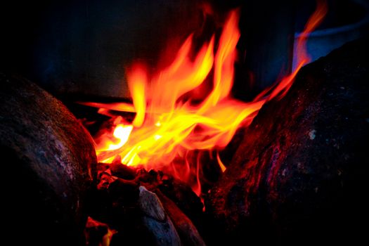 Bright and vivid flames dancing between rocks, captured in high contrast.
