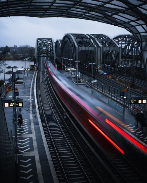 Free Long exposure captures train motion at Hamburg railway station with iconic bridge in the background. Stock Photo