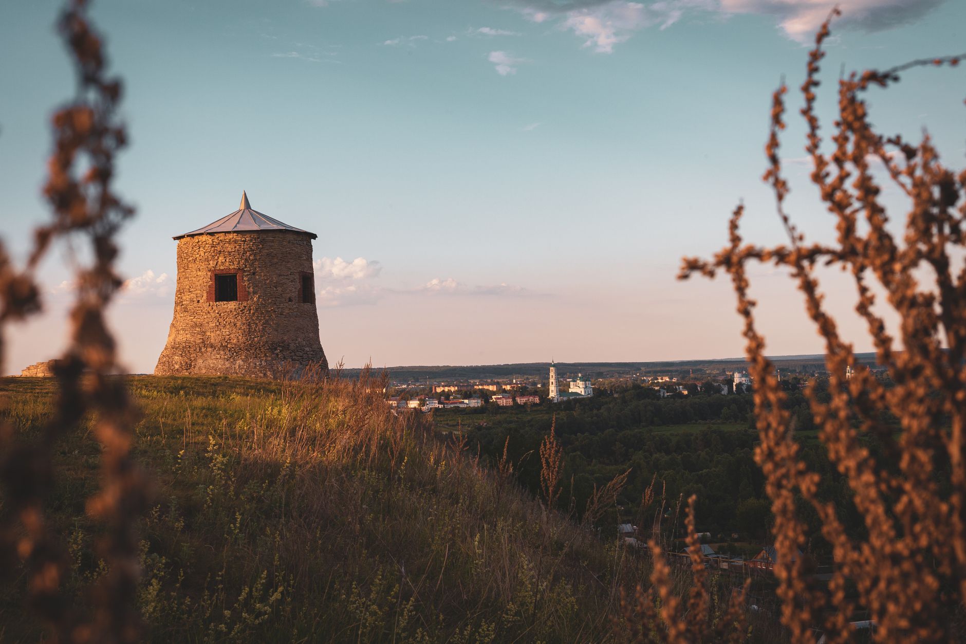 Landscape view from Elabuga Devil's Settlement hilltop with a historic tower against a sunset backdrop.