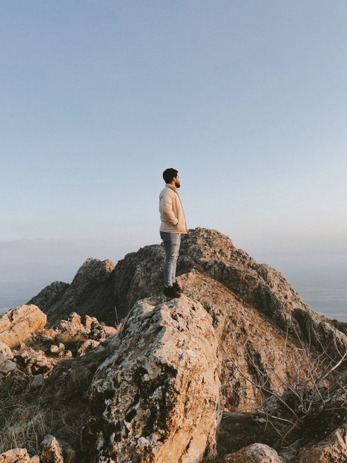 Free A man stands on a rocky mountain peak under a clear blue sky in Ranya, Iraq. Stock Photo