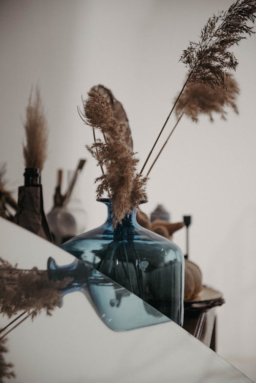Bottle with Grass Flowers Near Glass Table
