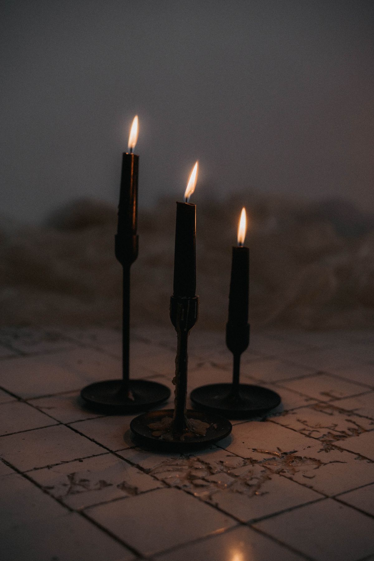 Black candlesticks of different heights with lit taper candles