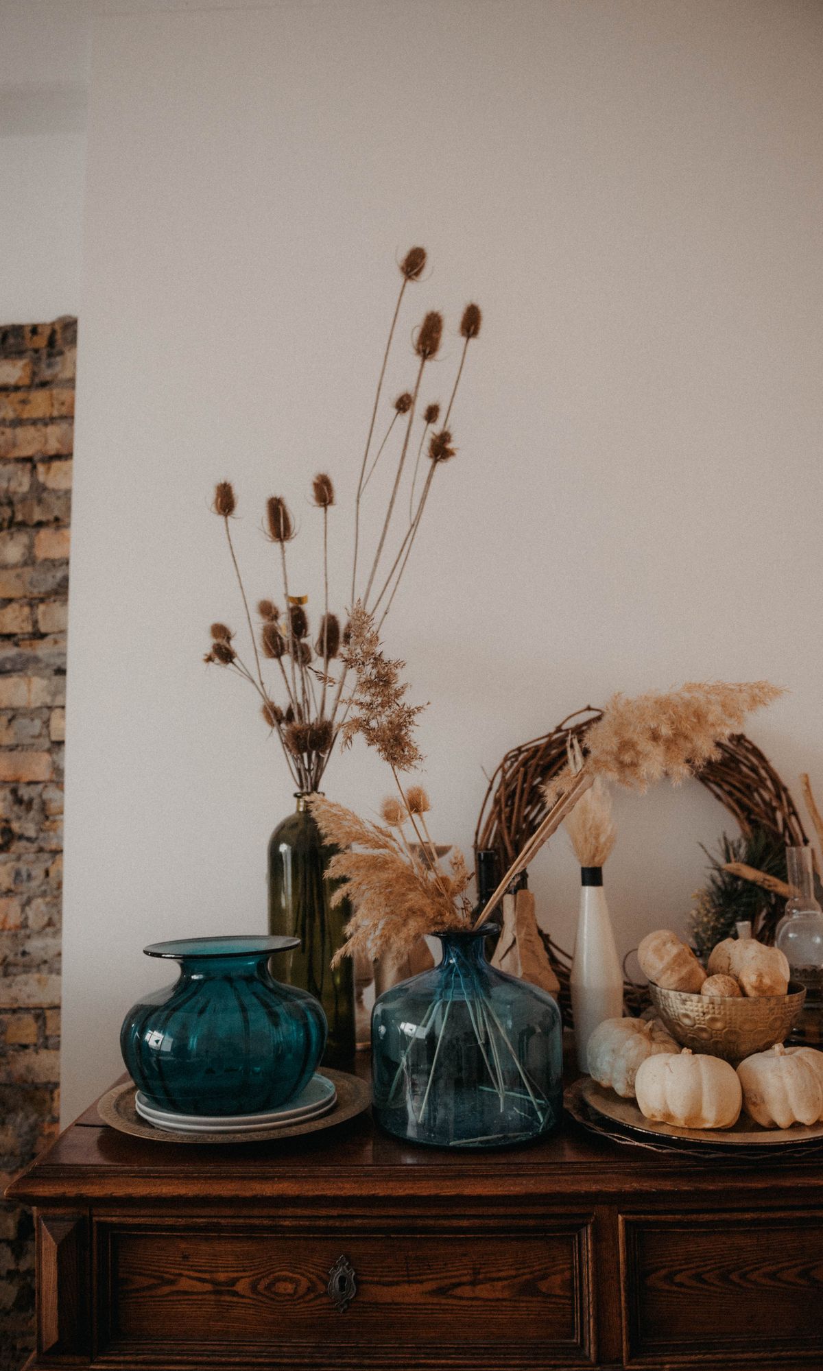 Charming fall-themed arrangement with dried plants, glass vases, and pumpkins on a wooden table. Stock Photo.