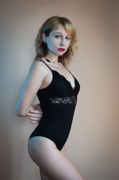 Elegant portrait of a woman in a black lace bodysuit, showcasing modern fashion and style.