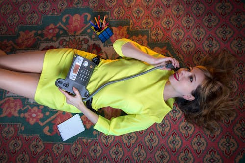 A Woman Lying Down on the Floor While using Telephone