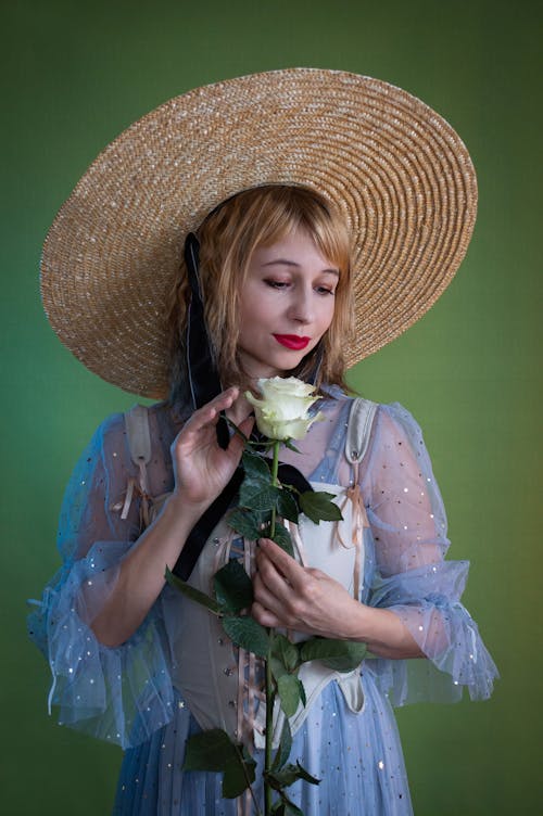 Woman Wearing a Hat Holding a White Rose