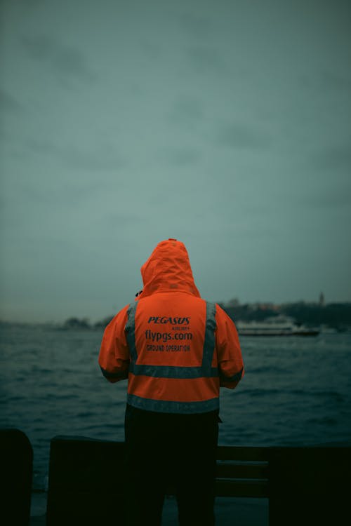 Person in Orange Hoodie Jacket Standing on Seaside