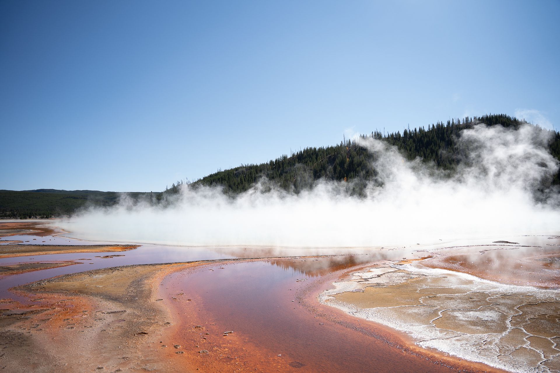 Stunning geothermal landscape in Yellowstone National Park with vibrant colors and steam rising.