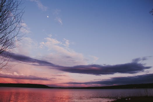 平静的湖面上，美丽的日出将鲜艳的天空色彩倒映在水中，营造出一片宁静的景象