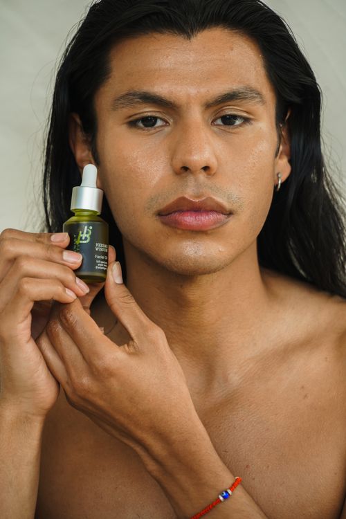 Free Young man with long hair showcasing a skincare product in a close-up shot. Stock Photo